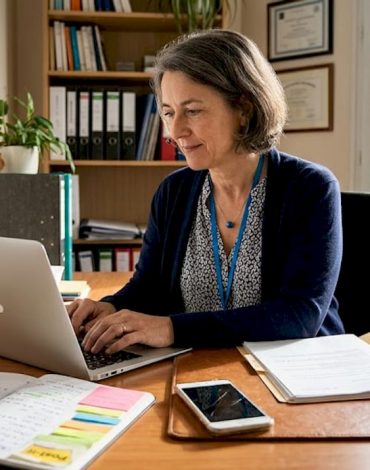 Une dirigeante de petite entreprise travaille avec sérieux devant son ordinateur, concentrée sur ses dossiers dans son bureau.