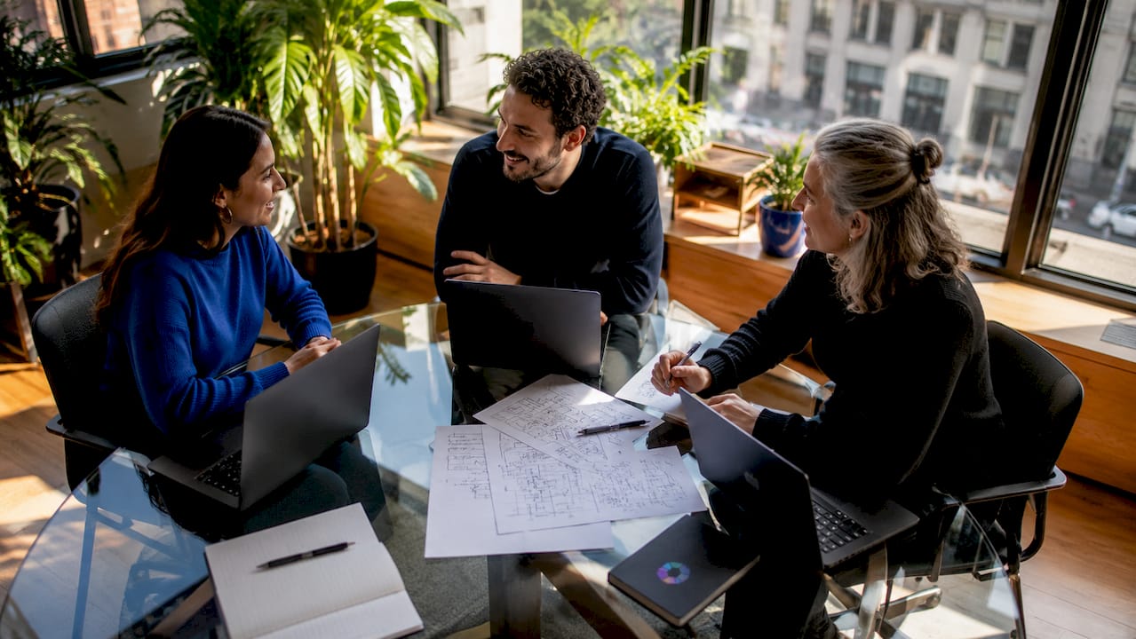 Une équipe aux profils variés échange autour d'une table, accompagnée par une intelligence artificielle qui facilite leur collaboration.