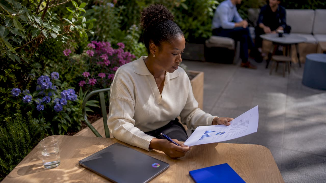 Une femme analyse des données financières sur son ordinateur, concentrée à son bureau.