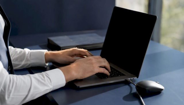 Des mains rédigent des mails de relance sur le clavier d’un ordinateur portable.